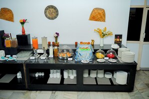 A buffet setup with various food items, utensils, and containers.