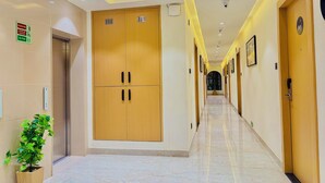 Un pasillo de hotel con puertas de madera, suelo de mármol e iluminación empotrada.
