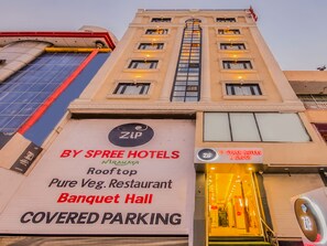A hotel sign with "ZIP" logo, "BY SPREE HOTELS", "Rooftop", "Pure Veg. Restaurant", "Banquet Hall", and "COVERED PARKING" text.