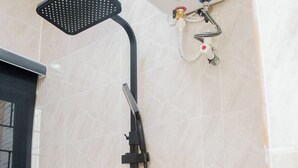 Une douche équipée d’un pommeau de douche à main et d’un panneau de commande fixé au mur.
