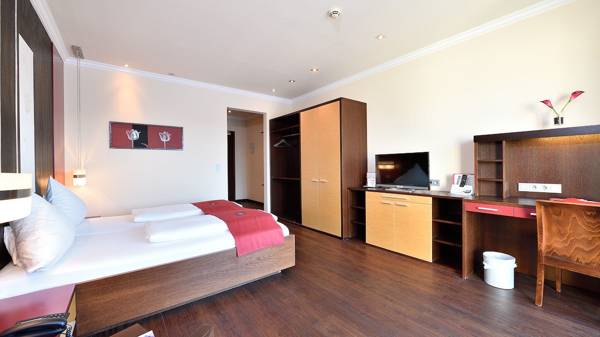 Una camera d'albergo con un letto, una scrivania, una televisione e un armadio.