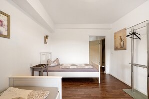 A bedroom with a bed, bedside table, and a hanging coat rack.