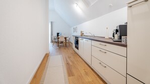 Une cuisine moderne avec des meubles blancs, un plancher en bois et un coin repas comprenant une table et des chaises.