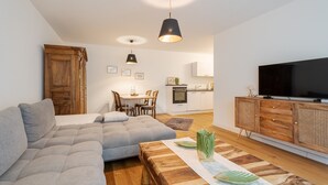 Ein modernes Wohnzimmer mit einem Ecksofa, einem Holzesstisch und einem Fernseher auf einer Holzkommode.