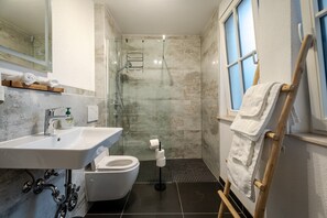 A bathroom with a shower, toilet, sink, and a towel rack.