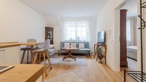 Una sala de estar moderna con un sofá, mesa de comedor, sillas, televisor y una escalera.