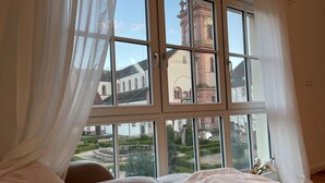Un dormitorio con un ventanal grande, una cama y vistas de un edificio con una torre de reloj.