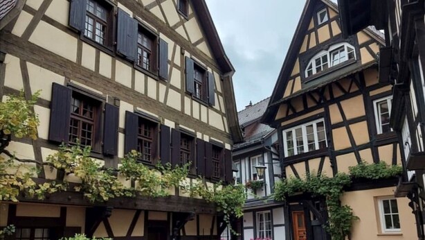 Un edificio tradicional con entramado de madera, múltiples ventanas y tejado inclinado.