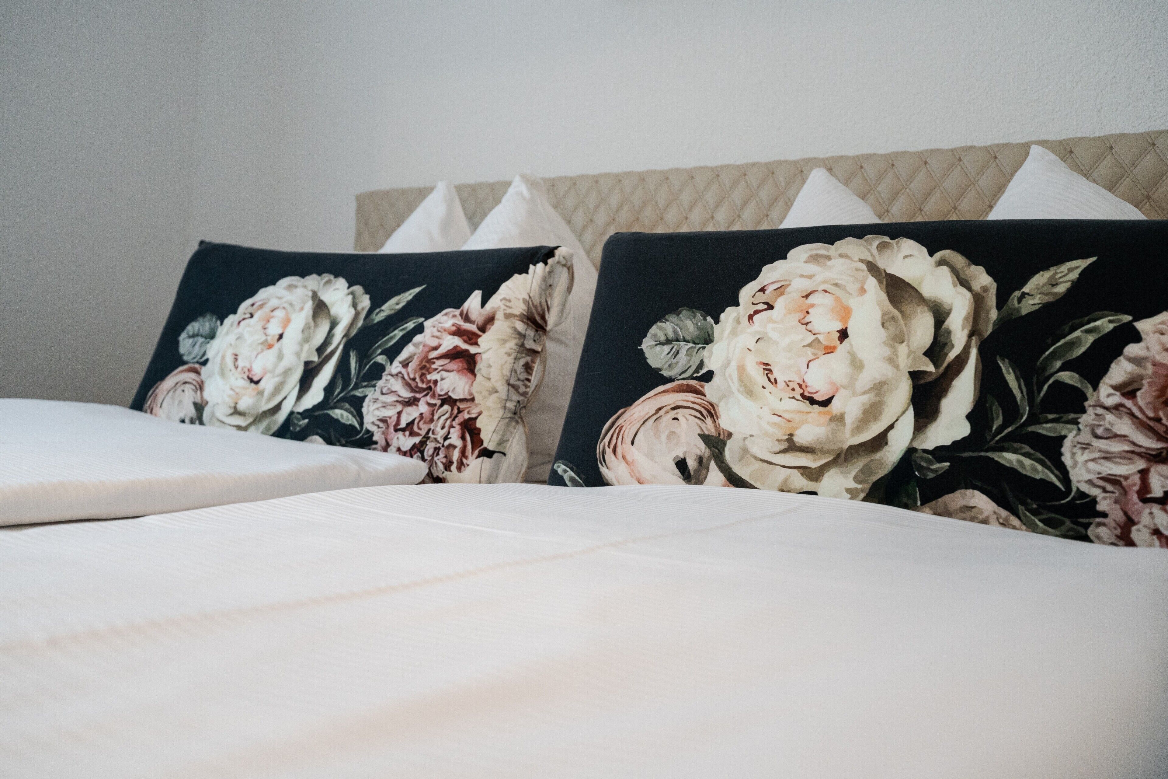 A bed with floral-patterned pillows and a headboard with a tufted design.