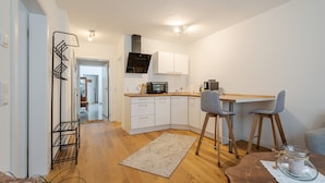 Una cocina moderna con armarios blancos, un microondas y una mesa de comedor de madera con dos sillas.
