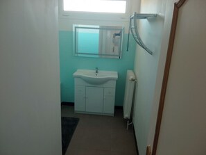 A small bathroom with a white sink, a mirror, and a window above the mirror.