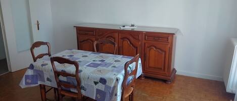 A dining area with a wooden table and chairs, a wooden cabinet, and a painting on the wall.