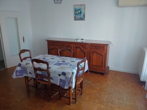 A dining area with a wooden table and chairs, a wooden cabinet, and a painting on the wall.