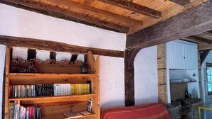 A rustic room with a wooden bed, a bookshelf, and a stone wall. - Gîte in the heart of the Gers - 2 hectares of tranquility 7 minutes from the Circuit de Nogaro (Magnan)
