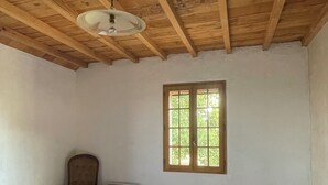 A bedroom with a wooden ceiling, a single window, a bed with a patterned bedspread, a chair, and a bedside table. - Gîte in the heart of the Gers - 2 hectares of tranquility 7 minutes from the Circuit de Nogaro (Magnan)