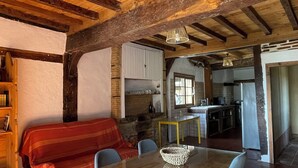 A rustic interior with a wooden dining table, chairs, a sofa, and a kitchen area. - Gîte in the heart of the Gers - 2 hectares of tranquility 7 minutes from the Circuit de Nogaro (Magnan)