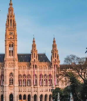 Um edifício histórico com torre do relógio, janelas em arco e múltiplices torres.
