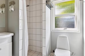 Ein Badezimmer mit Dusche, Toilette und einem Fenster mit Blick.