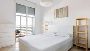 A bedroom with a large bed, a wooden side table, a hanging light fixture, and a view of the outside through a sliding door. - Terrazza Masini by Wonderful Italy (Bologna)