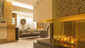 Un salon moderne avec une cheminée en verre, un canapé, une table basse et un mur décoratif.
