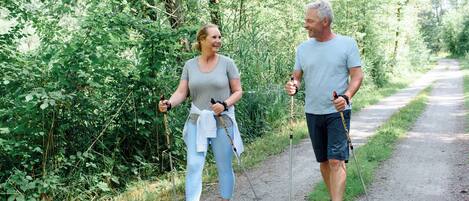 Two people walking on a dirt path surrounded by greenery.