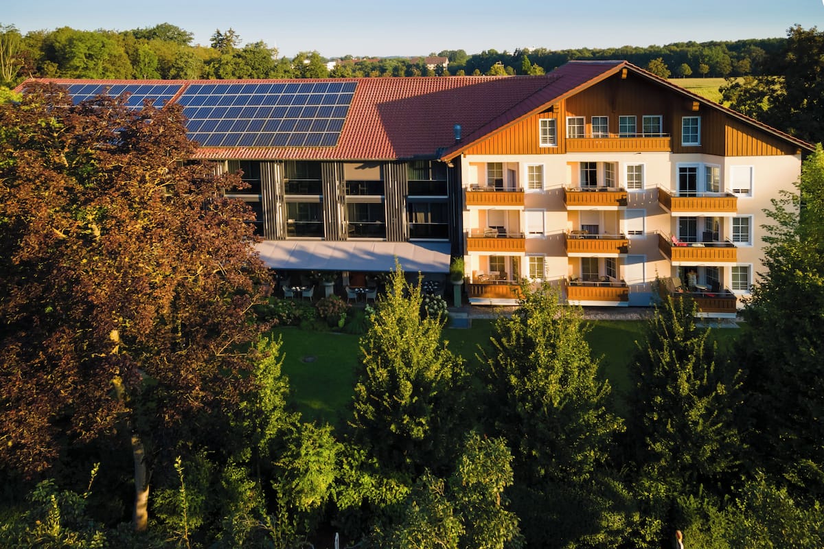 A modern building with a solar panel roof, multiple balconies, and a well-maintained garden.