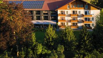 Un edificio moderno con techo de paneles solares, varios balcones y un jardín bien cuidado.