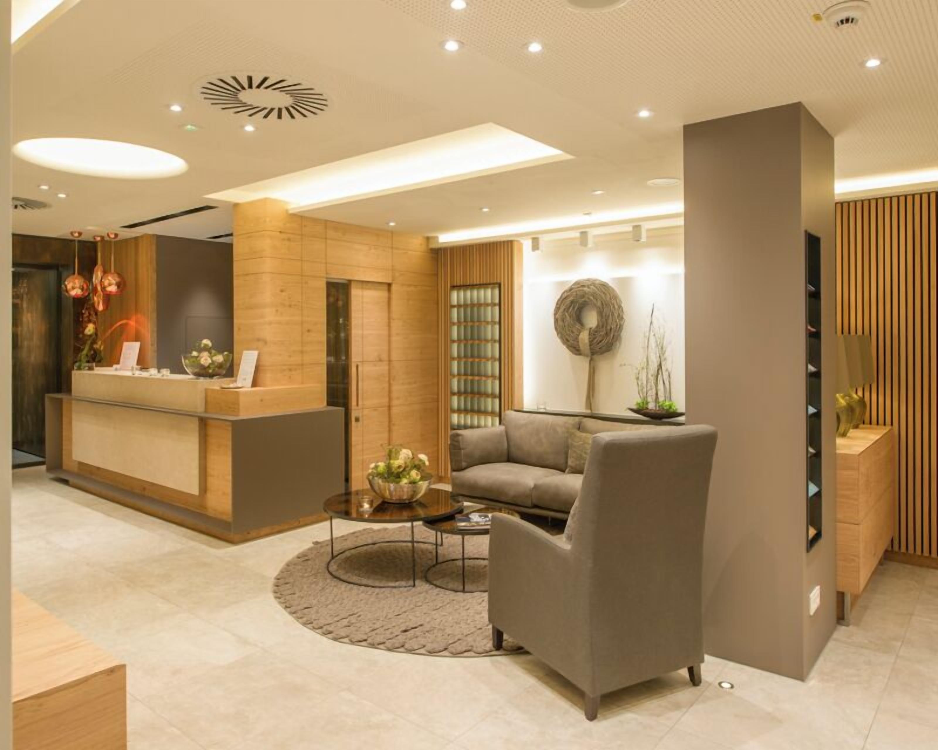 A modern reception area with a wooden reception desk, a grey sofa, and a round coffee table.