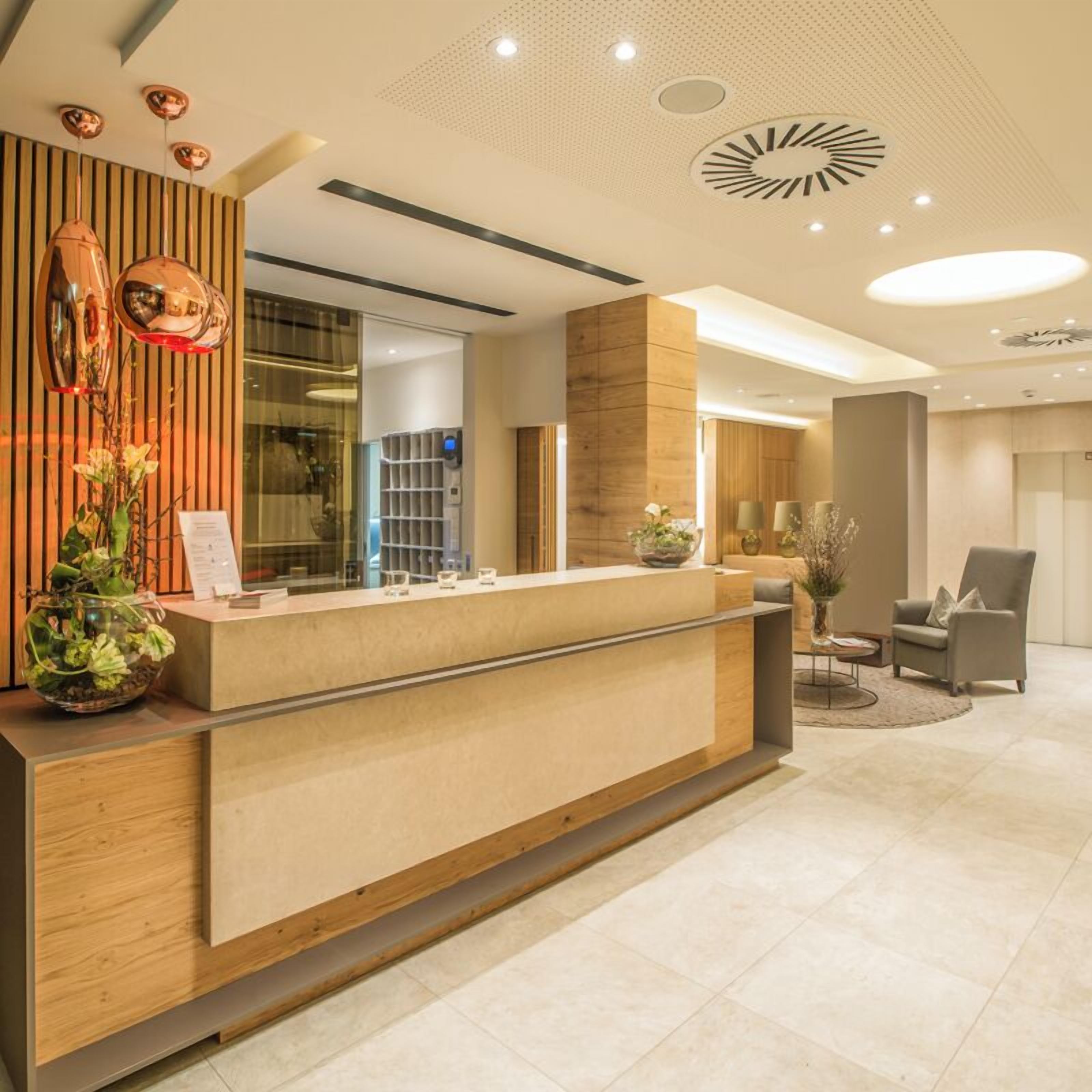 A modern reception desk with a wooden finish, a glass display case, and a potted plant.