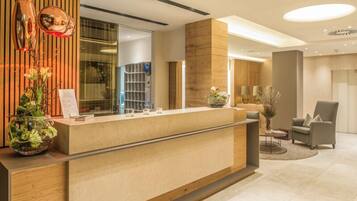 A modern reception desk with a wooden finish, a glass display case, and a potted plant.