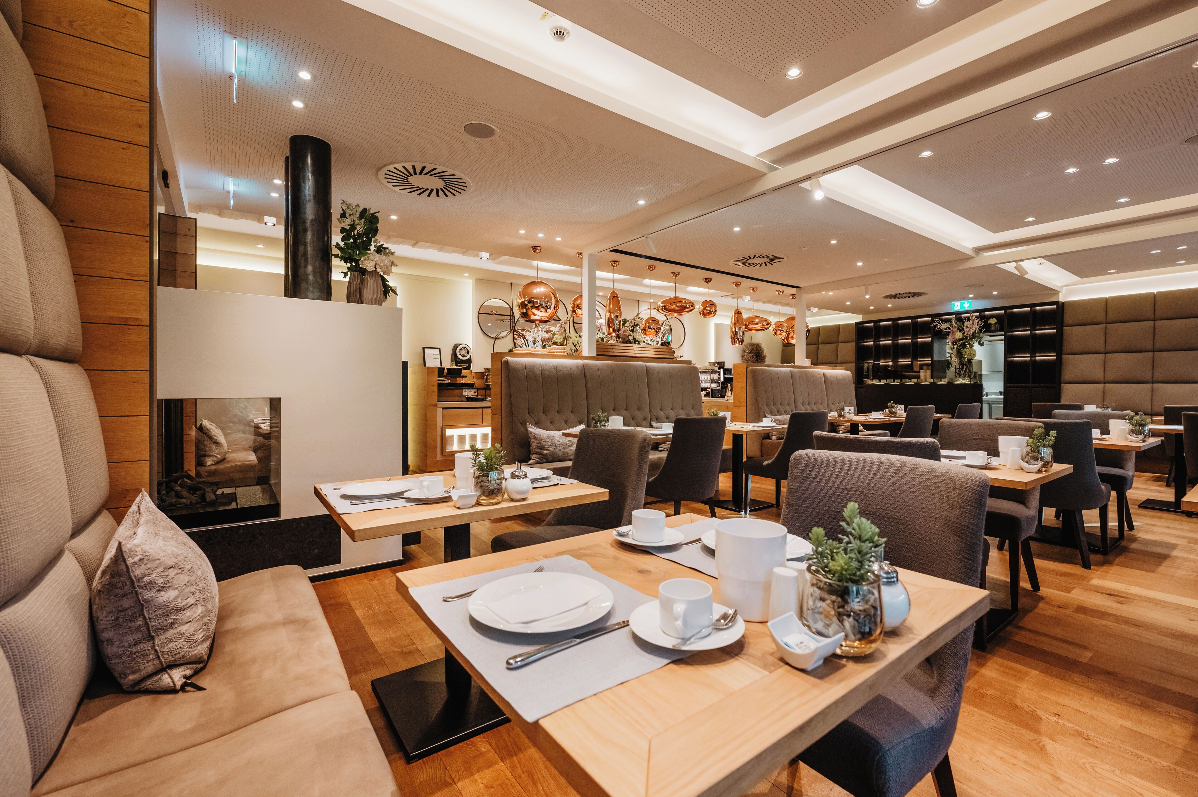 A modern restaurant with wooden flooring, cushioned seating, and contemporary decor.