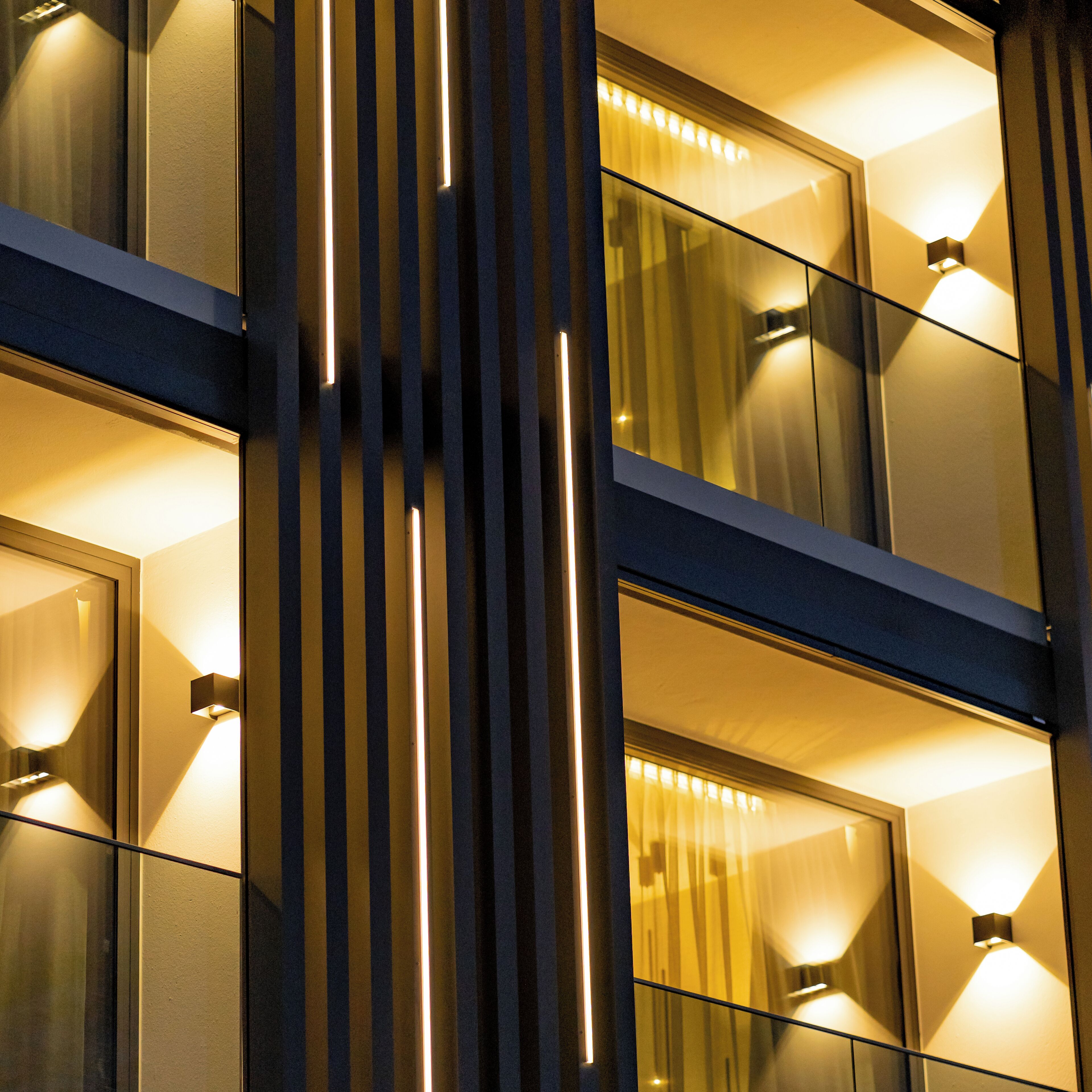 A modern building facade with vertical light strips and reflective glass windows.
