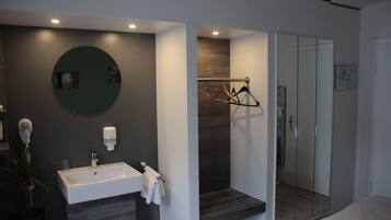 Un baño moderno con lavamanos, espejo y perchero.