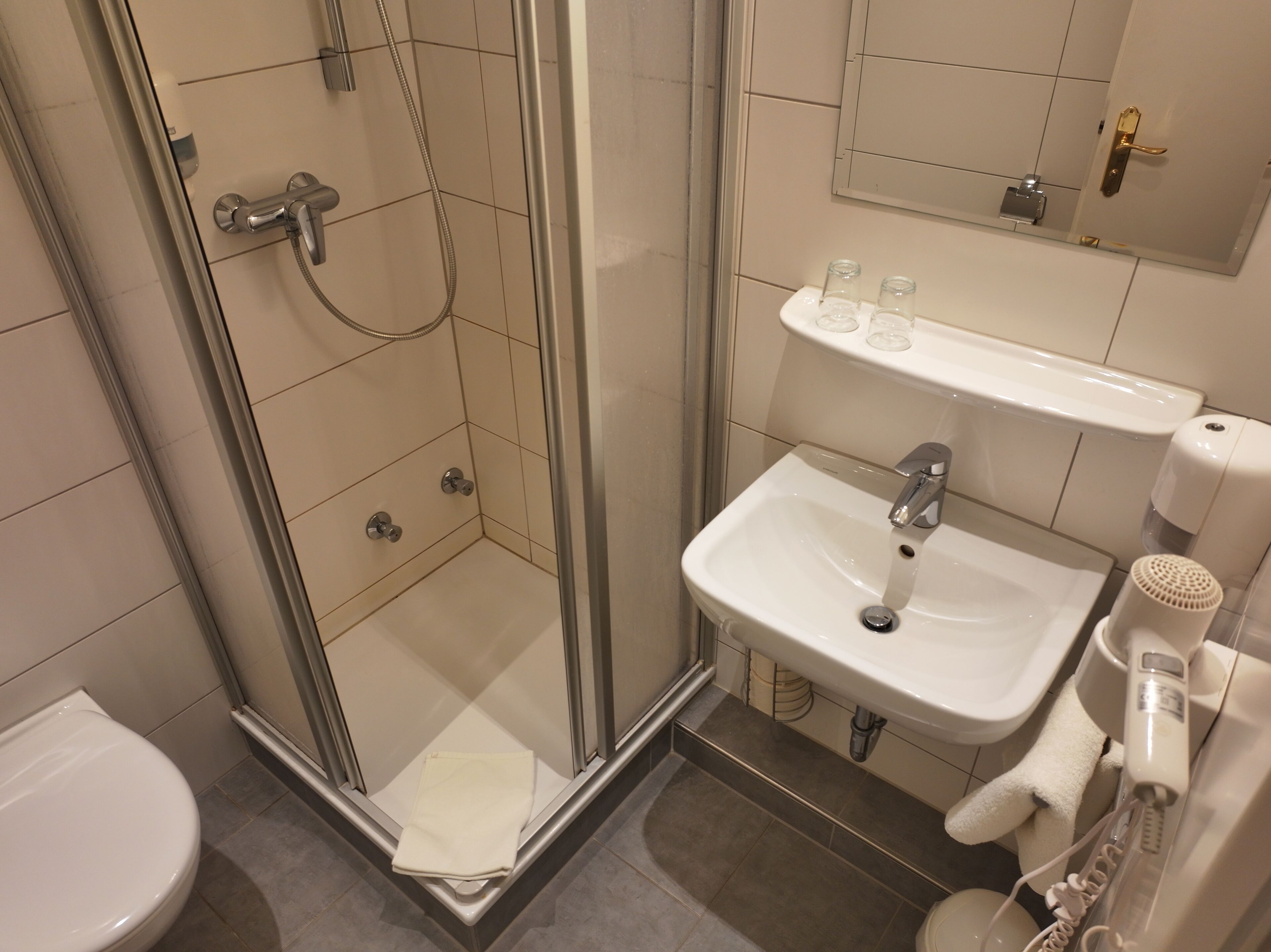 Un baño moderno con ducha de vidrio, lavamanos blanco y retrete.