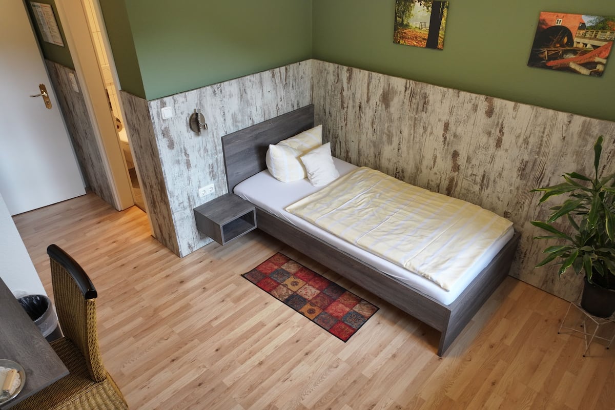 A bedroom with a bed, nightstand, chair, and a small table.
