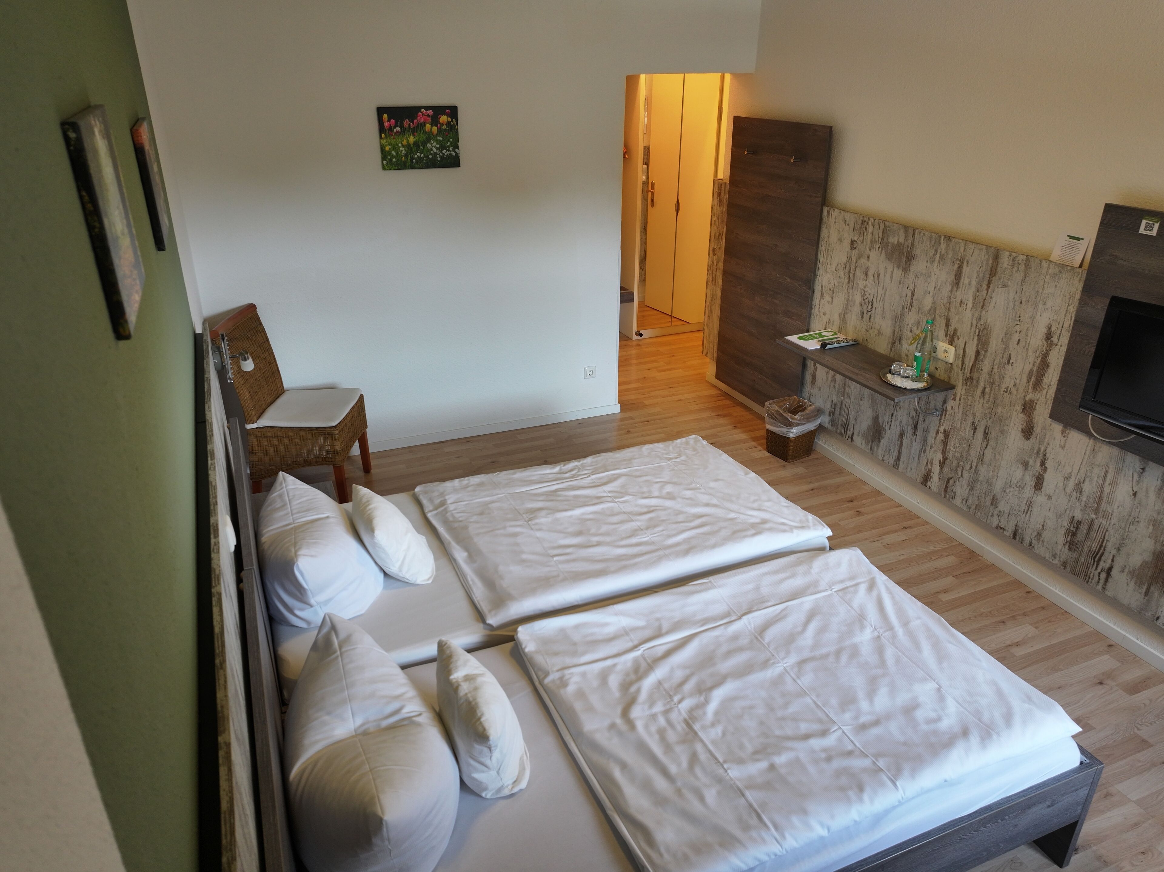 A hotel room with two beds, a small chair, a TV, and a wooden cabinet.