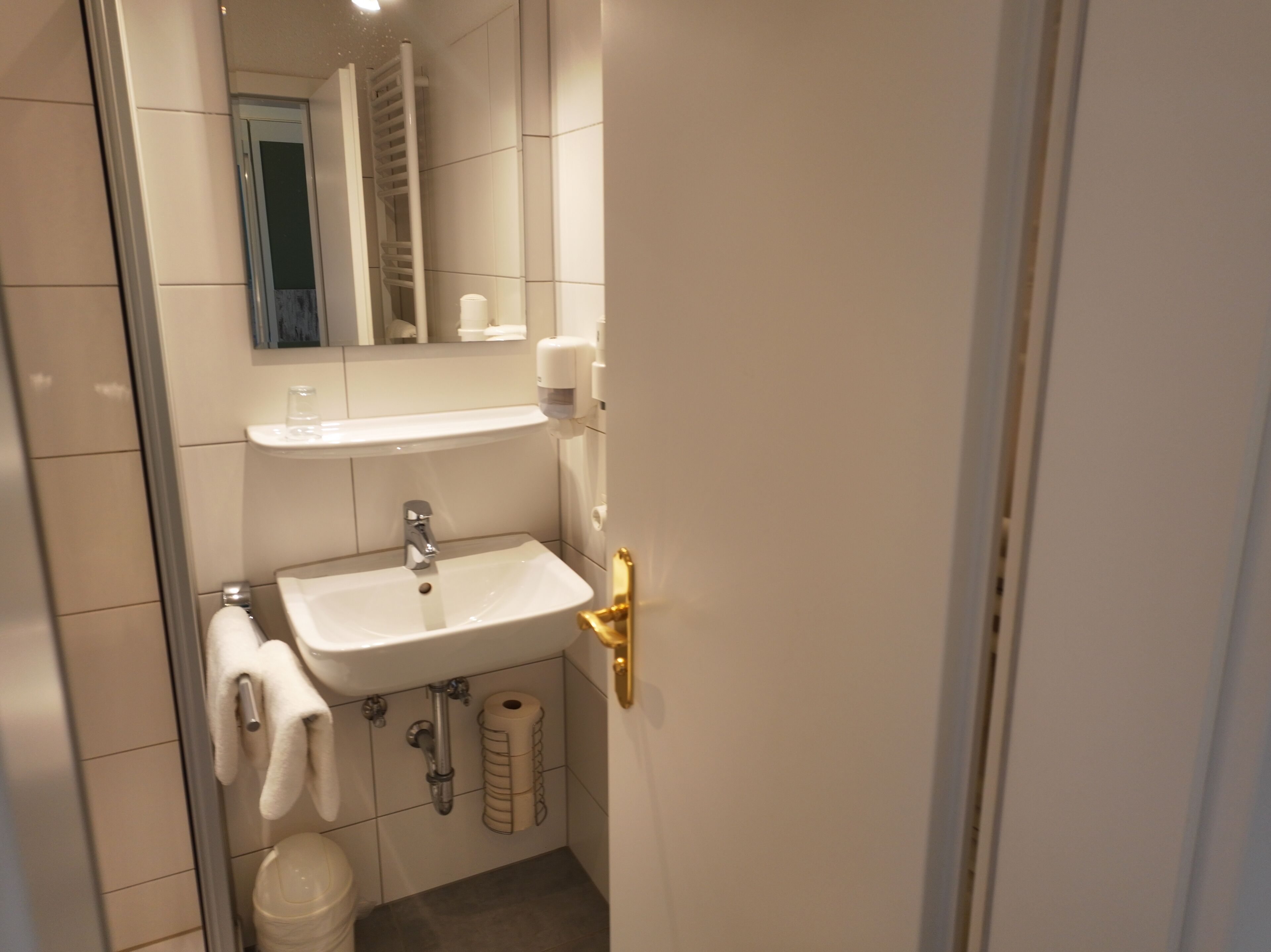 A bathroom with a white sink, a towel rack, a toilet, and a mirror.
