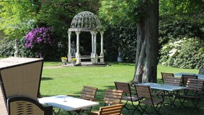 Ein Garten mit einem Pavillon, Holztischen und -stühlen.