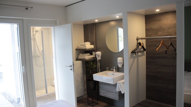 Ein modernes Badezimmer mit Dusche, Waschbecken und Handtuchhalter.