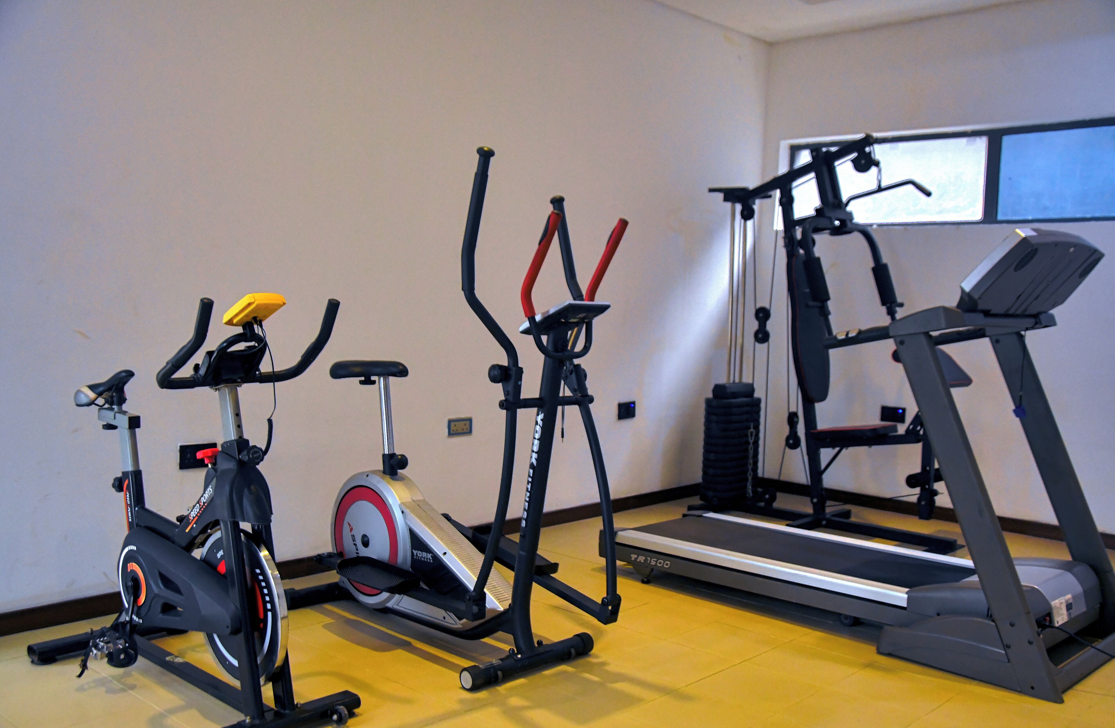 A gym with an elliptical trainer, a stationary bike, a stair climber, and a treadmill.
