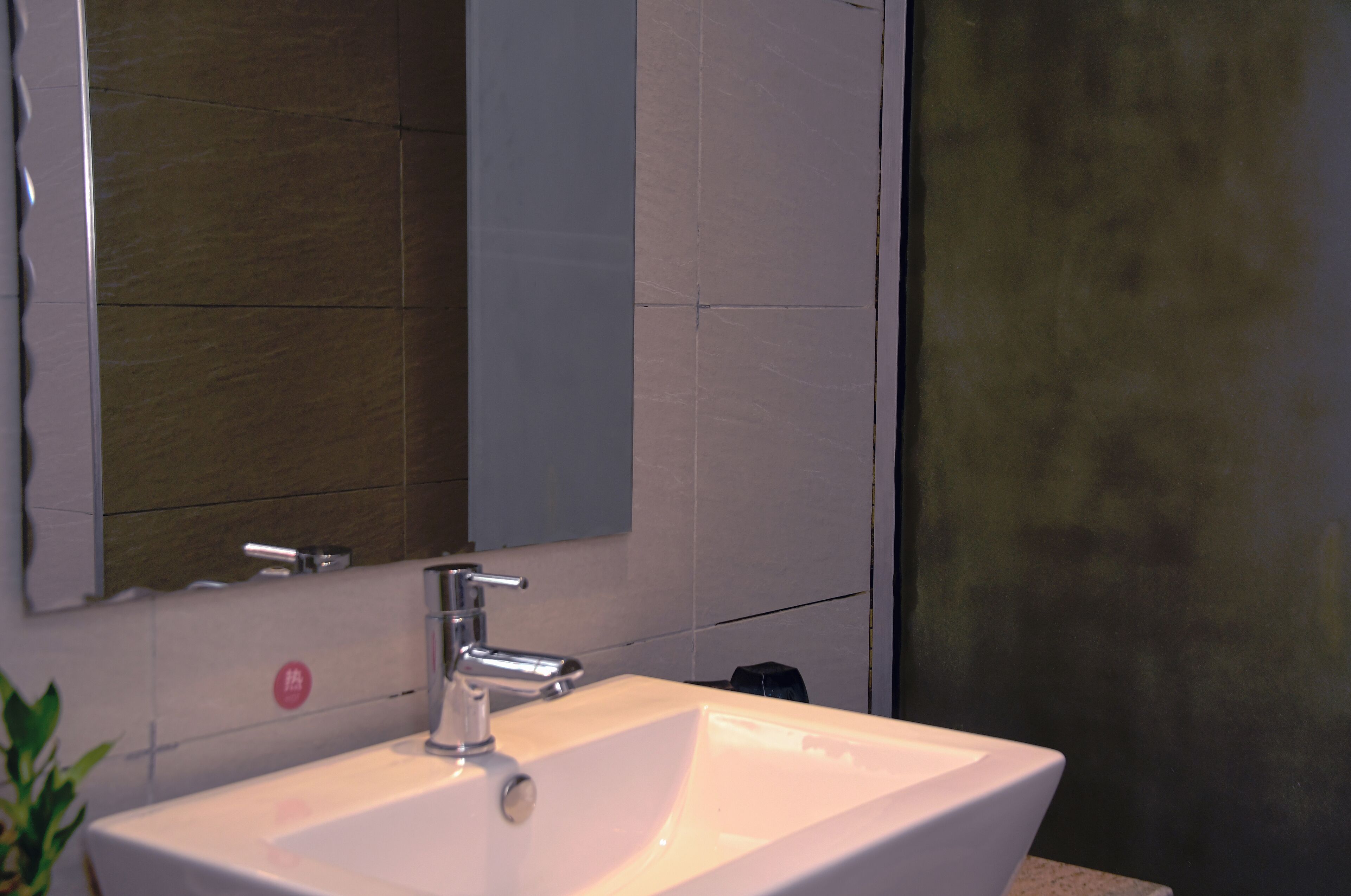 A bathroom with a white sink, a mirror, and a wall with a textured finish.