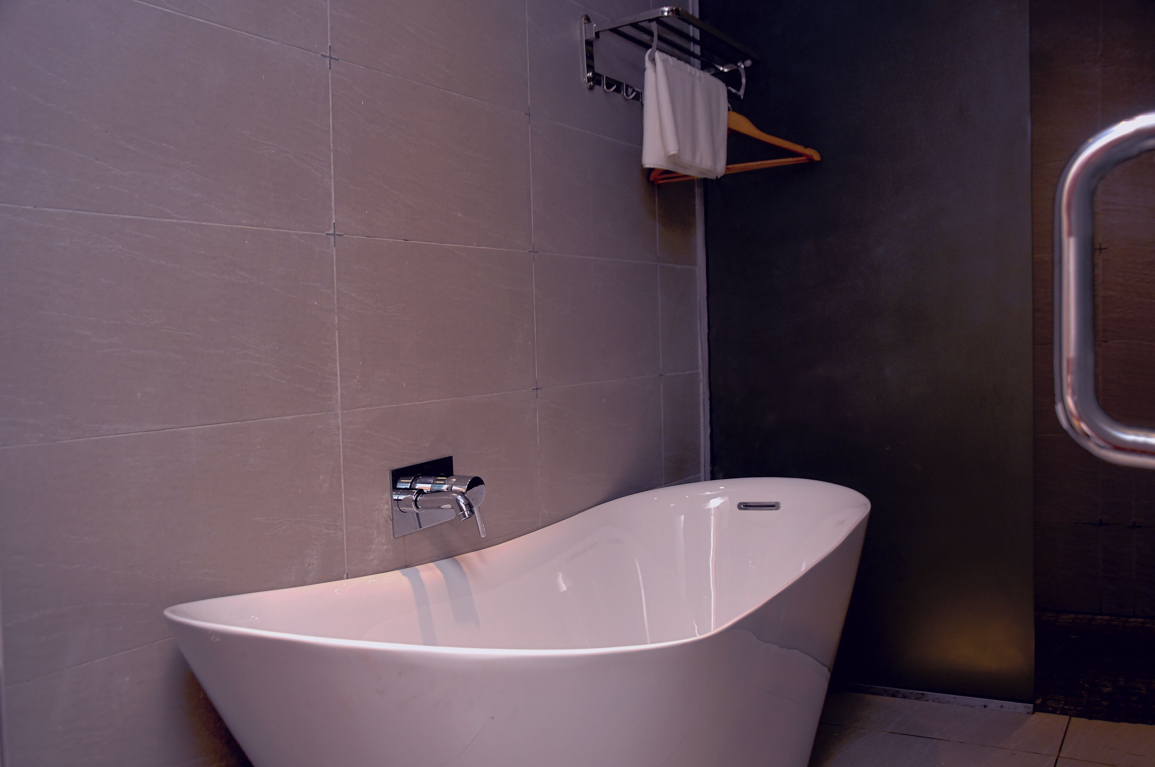 A modern bathroom with a freestanding bathtub, a towel rack, and a shower area.