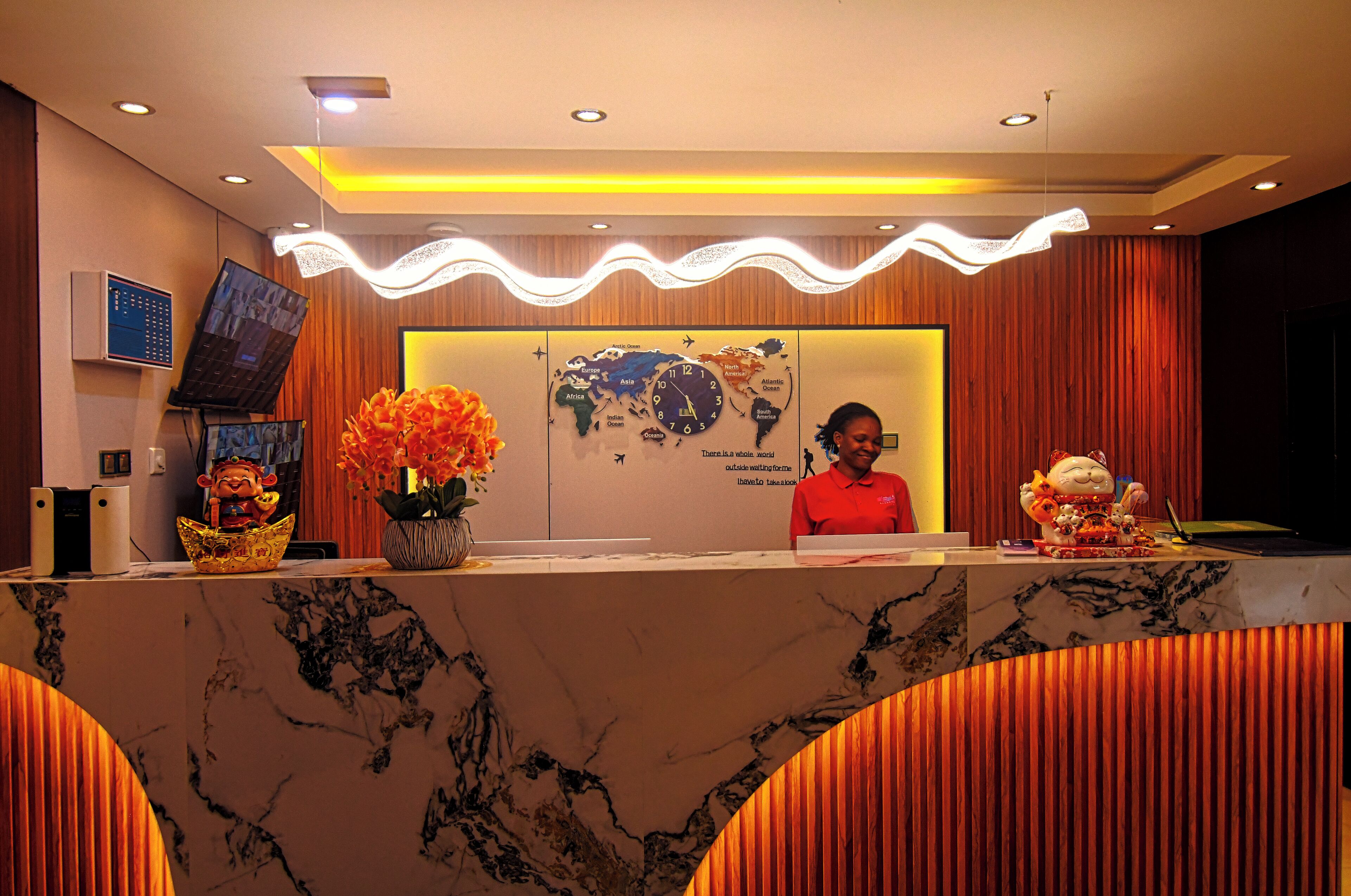 A hotel reception desk with a world map, a clock, and a digital screen.