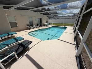 A covered swimming pool with lounge chairs, a table, and chairs.