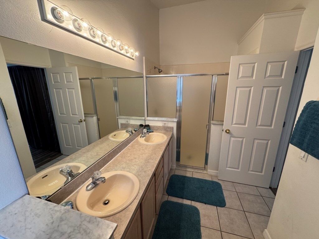 Un baño con dos lavamanos, un espejo grande y una zona de ducha.