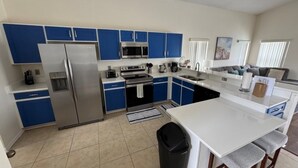 A modern kitchen with blue cabinets, stainless steel appliances, and a white island. - Lakeview Villa 5 Bedroom Home (Davenport)