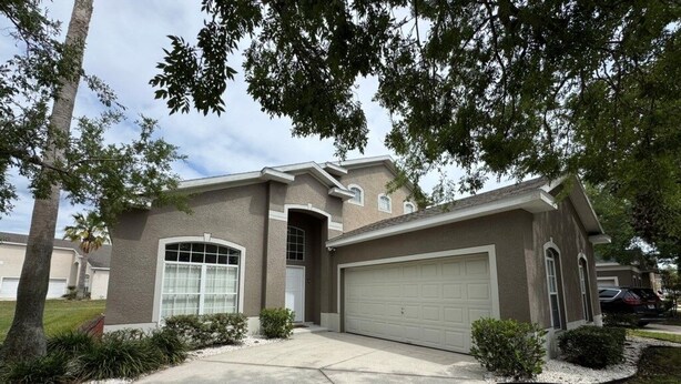 A residential house with a garage, driveway, and landscaping. - Lakeview Villa 5 Bedroom Home (Davenport)