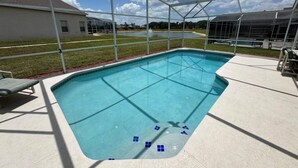 A covered swimming pool with a clear view of the surrounding area, including a building and a grassy field. - Lakeview Villa 5 Bedroom Home (Davenport)