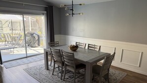 Un espace repas comprenant une table et des chaises, un lustre et une vue sur l’extérieur.