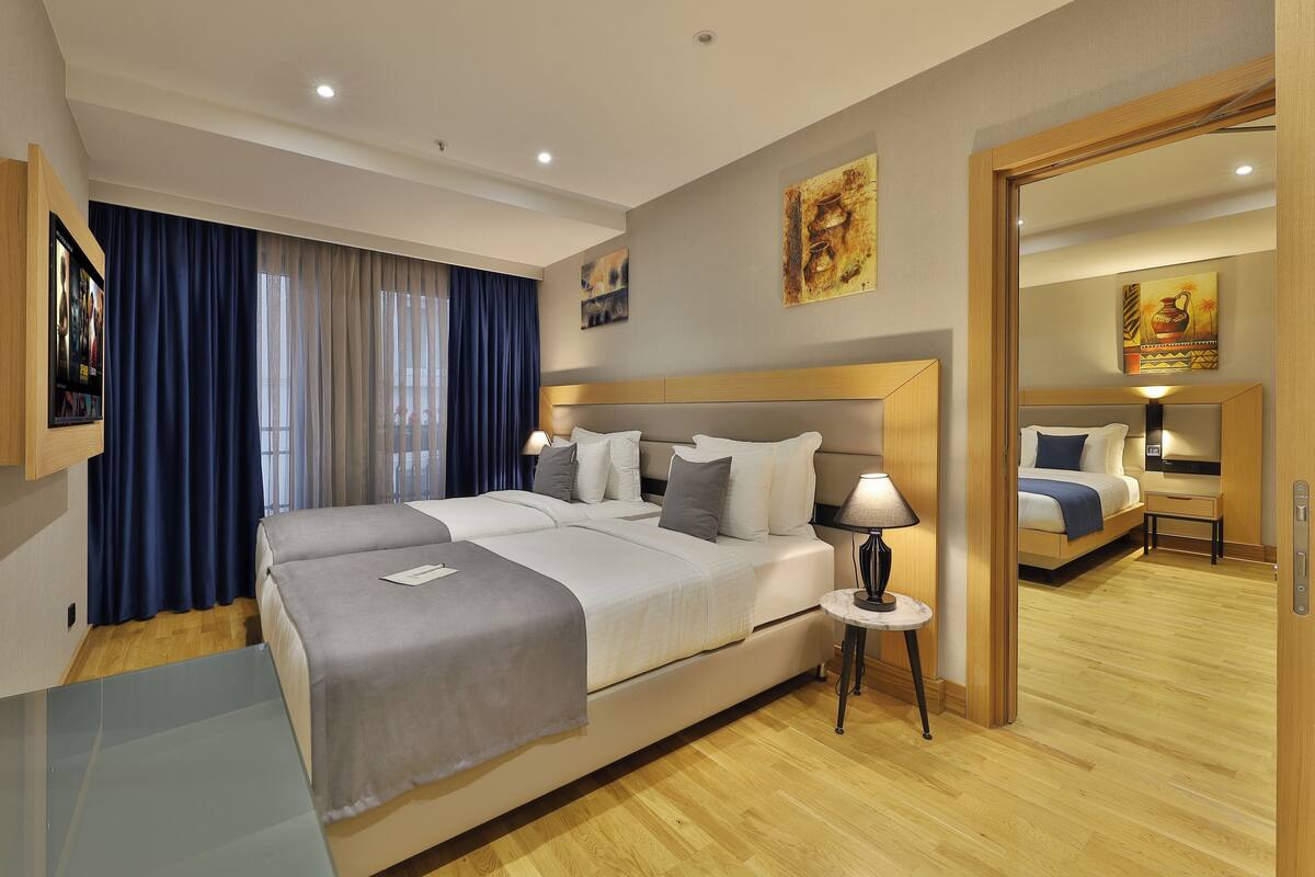 Una habitación de hotel moderna con una cama grande, mesitas de noche, un espejo y obras de arte en las paredes.